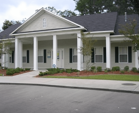 A white house with a grey roof and a porch.
